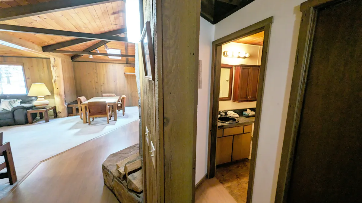 A wide view of a cozy living room with wooden beams, comfortable seating, and a view into the kitchen area. The arrangement is perfect for group gatherings, playing games, or relaxing after a day of exploration.