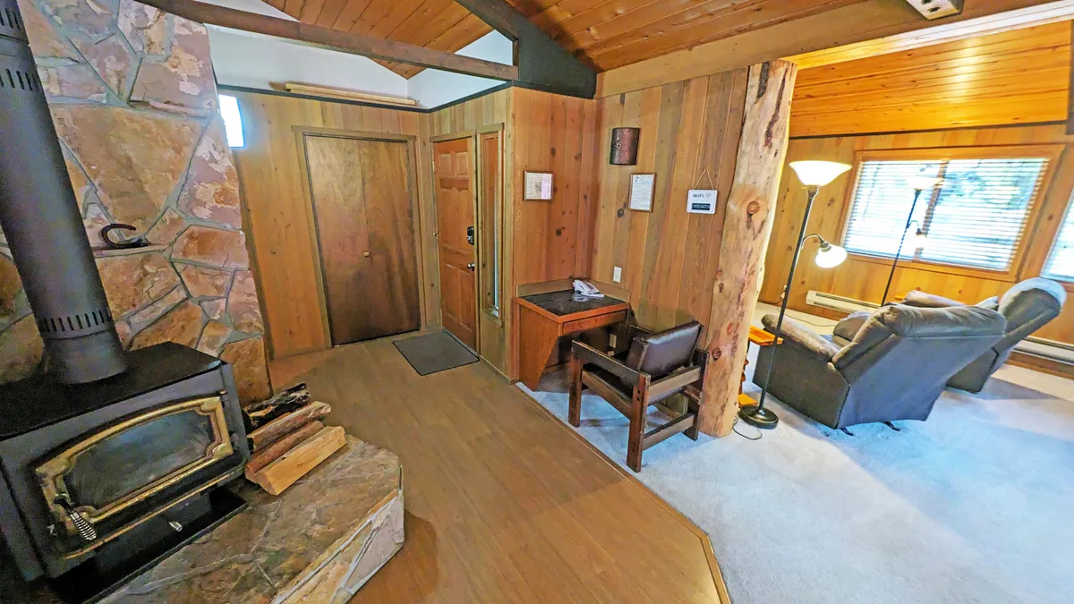 A warm and inviting living space with a stone fireplace, wood-paneled walls, and a comfortable seating area. The area is bathed in soft light, evoking a sense of relaxation and comfort perfect for winding down after outdoor fun.