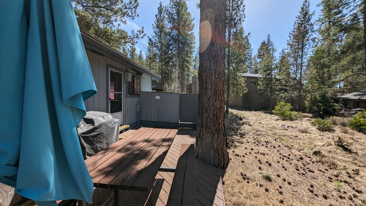 This exterior image features a wooden deck surrounded by trees, an outdoor grill, and a fence, capturing the tranquil setting of the patio and BBQ area. The grill and open-air space evoke relaxation and outdoor dining possibilities described in the section.